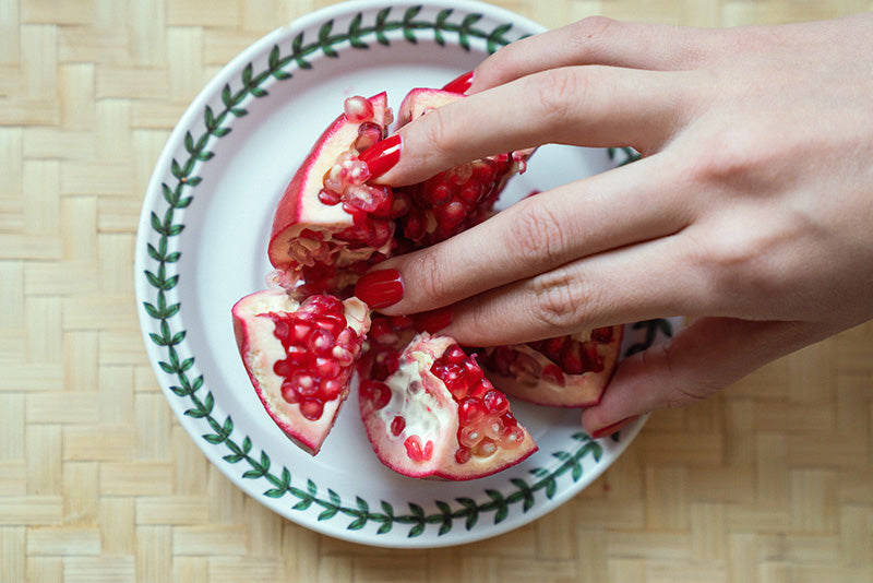 hand in pomegranate seeds on a plate
