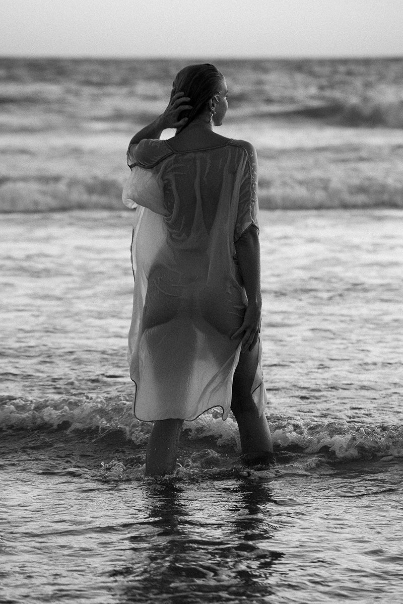 woman in sensual clothing at the beach with feet in water